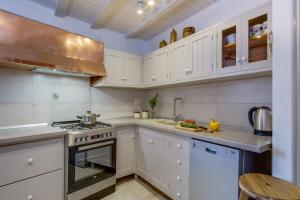 a kitchen with white cabinets and a stove top oven at House Mihaela in Miholašćica
