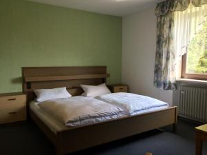 una camera da letto con un letto con lenzuola bianche e una finestra di Pension Berghof a Schönsee
