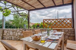 a table and chairs on a patio with a stone wall at House Mihaela in Miholašćica