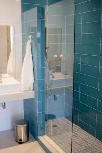 y baño con ducha de azulejos azules. en RestlessWave, en Peniche