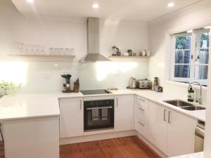 a white kitchen with a sink and a stove at 4 bedroom house - Walk to Southbank in Brisbane