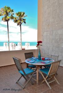 une table et des chaises avec une table et des palmiers dans l'établissement AMAZING FRONTAL BEACH APARTMENT #Traveller's Awards2023, à Cadix