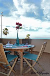 AMAZING FRONTAL BEACH APARTMENT #Traveller's Awards2023 في كاديز: طاولة مع كراسي و مزهرية عليها زهور