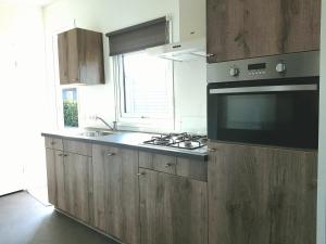 eine Küche mit Holzschränken, einem Herd und einer Mikrowelle in der Unterkunft Chalet 15 (Resort Venetië) in Giethoorn + 6 Fotos