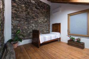 a bedroom with a bed and a stone wall at Guest House Seme Di Faggio in Miasino +49 photos