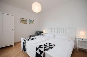 a bedroom with a white bed with a black and white blanket at Apartment RUZA in Lopar