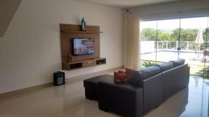 een woonkamer met een bank en een flatscreen-tv bij CASA UTOPIA ESCARPAS do LAGO in Capitólio