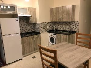 a kitchen with a table and a white refrigerator at Al Jawad Suites 2 in Aqaba