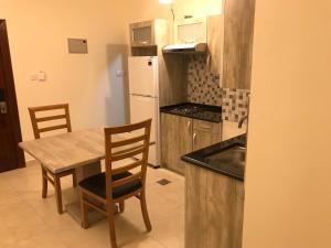 a kitchen with a wooden table and chairs and a sink at Al Jawad Suites 2 in Aqaba