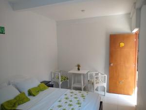a white bedroom with a bed and a table at Hostal Palohe Taganga in Taganga
