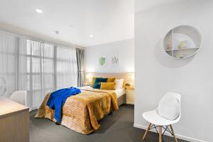 a white bedroom with a bed and a chair at Deluxe Apartment with Sofa Bed - Sleeps 2 in Auckland