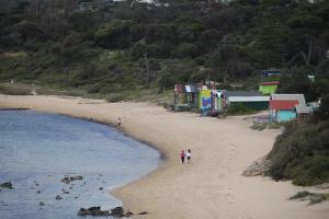 people walking on a beach next to a body of water at Mornington Motel in Mornington
