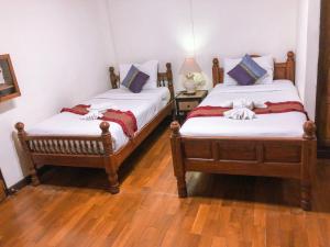 Habitación con 2 camas individuales y suelo de madera. en Rustic Guest House, en Chiang Mai