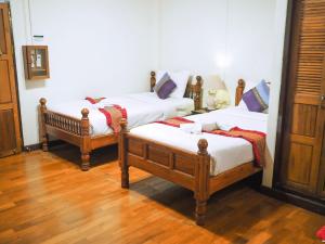 two twin beds in a room with wooden floors at Rustic Guest House in Chiang Mai