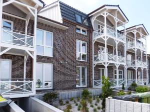 an apartment building with white balconies and a courtyard at Weiße Düne Ferienwohnung *Weiße Düne 7* in Wittdün