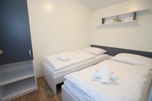 two beds in a small room with white sheets at Camping Bunculuka in Baška