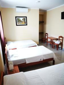 a room with two beds and a table and chairs at Hostal Cordillera Azul in Tarapoto