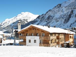 a building in the snow with a mountain in the background at Chalet Anna Maria in Lech am Arlberg