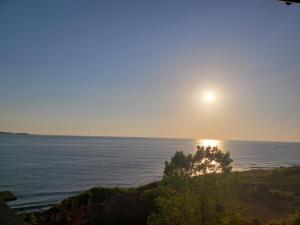 a sun setting over the ocean with a tree at Guest House Evtimov in Primorsko