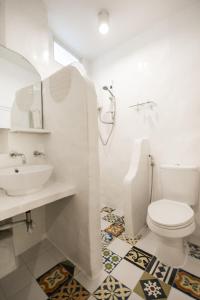 a white bathroom with a toilet and a sink at Lugar Bonito Hotel in Boracay