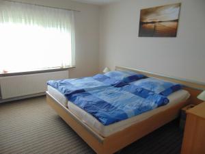 a bedroom with a bed with blue sheets and a window at Ferienwohnung Ehrich nahe Otterndorf in Belum