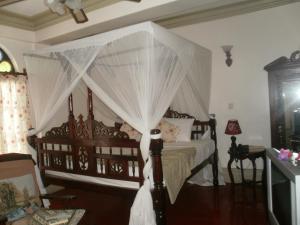 ein Schlafzimmer mit Himmelbett und weißen Vorhängen in der Unterkunft Asmini Palace Hotel in Zanzibar City