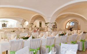 a room with white chairs and tables with flowers at Gutshotel Odelzhausen in Odelzhausen