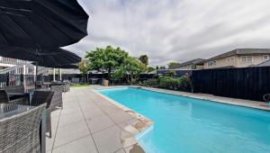 a swimming pool with umbrellas next to a house at Ashford Motor Lodge in Christchurch