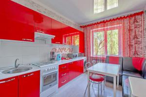 a red kitchen with a table and red cabinets at Cozy apartment on Rozybakiev 145. Atakent in Almaty