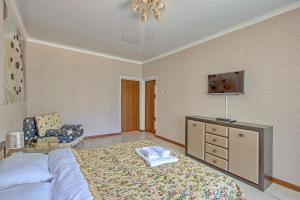 a bedroom with a bed with a dresser and a chair at Cozy apartment on Rozybakiev 145. Atakent in Almaty