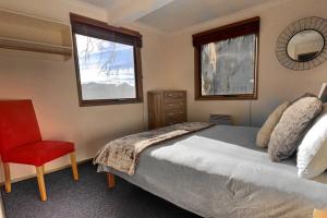 a bedroom with a bed and a chair and two windows at snowy river in Dinner Plain