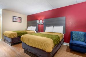 twee bedden in een kamer met een rode muur bij Econo Lodge in Chattanooga