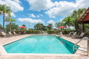 einen Pool mit Stühlen und Sonnenschirmen in einem Resort in der Unterkunft Clarion Inn Ormond Beach at Destination Daytona in Ormond Beach