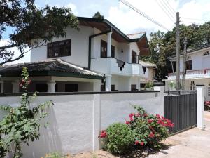 a white house with a fence and flowers at Blue Ridge Homestay in Kandy