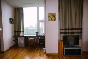 um quarto com uma secretária, uma televisão e uma janela em New Wave Vung Tau Hotel em Vung Tau
