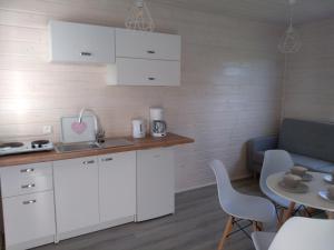 uma cozinha com armários brancos, uma mesa e um sofá em Domki na górce em Kolczewo