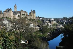 una ciudad con un castillo en una colina junto a un río en Le trou dans le mur, en Uzerche