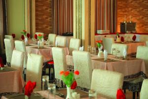 - une salle à manger avec des tables, des chaises et des fleurs rouges dans l'établissement Tiffany Diamond Hotels - Mtwara, à Mtwara