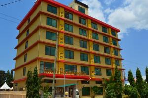 a tall yellow building with a red roof at Tiffany Diamond Hotels - Mtwara in Mtwara