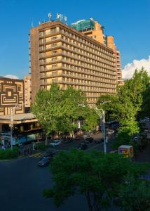 een groot gebouw in een stad met een parkeerplaats bij Ani Plaza Hotel in Jerevan