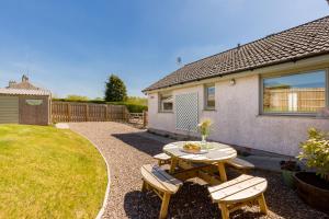 a patio with a table and chairs in a yard at Lammerlaw Farm Cottage in Biggar