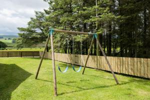 a swing in a yard next to a fence at Lammerlaw Farm Cottage in Biggar
