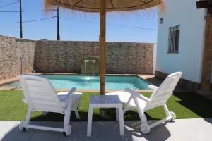 a table and two chairs and an umbrella next to a pool at Chalet carril de los pareja in Conil de la Frontera