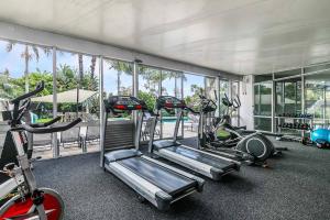 a gym with several tread machines in a room at One Bedroom Apartment - Pool, Gym & Tennis Courts! in Auckland
