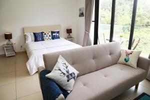 een woonkamer met een bank en een bed bij STYLISH COZY HOME @ MIDHILLS GENTING | 8 MINS TO SKYWAY/GPO in Genting Highlands