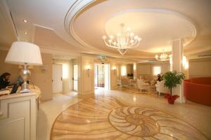 un'ampia hall con lampadario pendente e pavimento in legno di Palace Hotel Vieste a Vieste