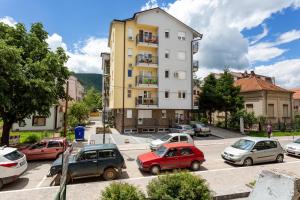 a parking lot with cars parked in front of a building at Apartmani Pezerović in Soko Banja