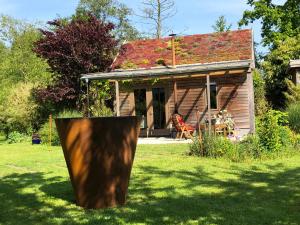 una pequeña casa con un tronco de árbol en el patio en De Aagt-Tuyn, en Schoorl