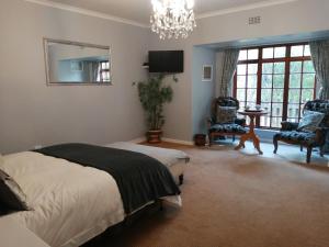 1 dormitorio con cama y lámpara de araña en Mooring House, en Somerset West