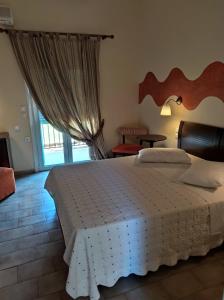 a bedroom with a large bed and a window at Sunrise Hotel Nikiana Lefkada in Nikiana